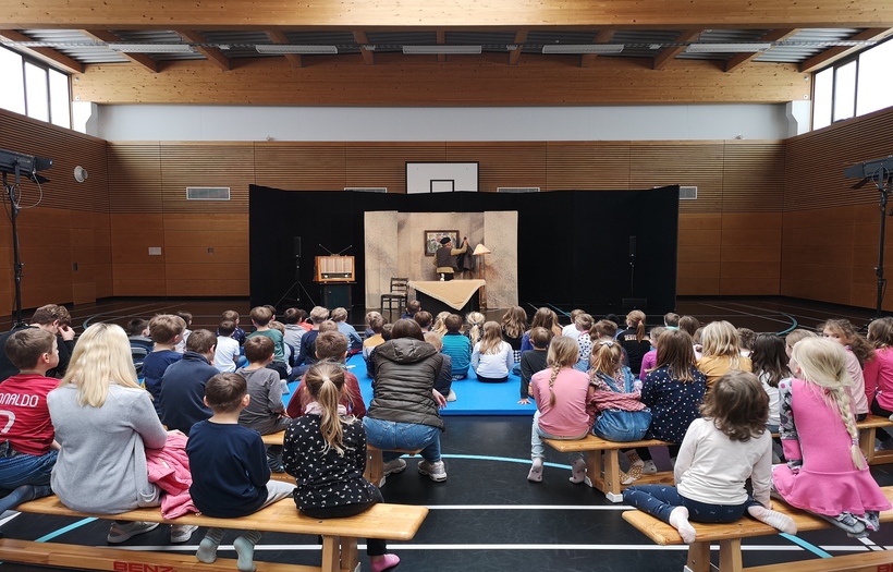 Für den DPFA-Regenbogen-Hort Zwenkau wird ein Theaterstück wird in einer Turnhalle aufgeführt und die Kinder schauen gebannt auf die Bühne.