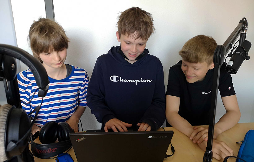 Drei Schüler, ein Mädchen und zwei Jungen, stehen während des Hörspielprojektes des DPFA-Regenbogen-Gymnasiums Zwenkau im Studio.
