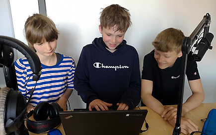 Drei Schüler, ein Mädchen und zwei Jungen, des DPFA-Regenbogen-Gymnasiums Zwenkau stehen während des Hörpsielprojektes im Studio.