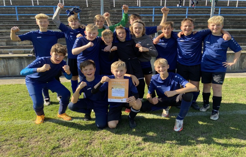 Die Jungen der Fussball Manschaft des DPFA Regenbogen Gymnasiums Zwenkau halten zusammen stolz die Gewinnerurkunde des Fussballturniers hoch. Sie jubeln und freuen sich sehr.