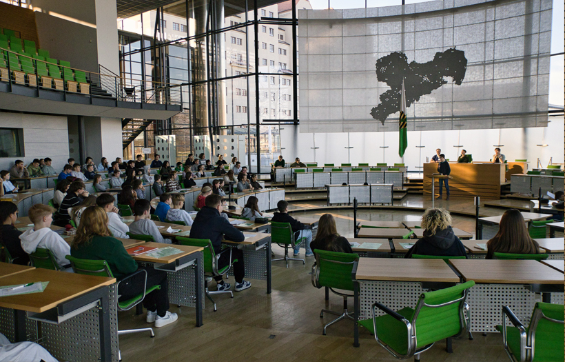 Im Plenarsaal des sächsischen Landtages sitzen die Schüler:innen auf den Plätzen der eigentlichen Abgeordneten.