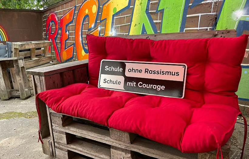 Präsentiert auf einer roten Couch sticht das Label des Netzwerkes gegen Rassismus heraus.